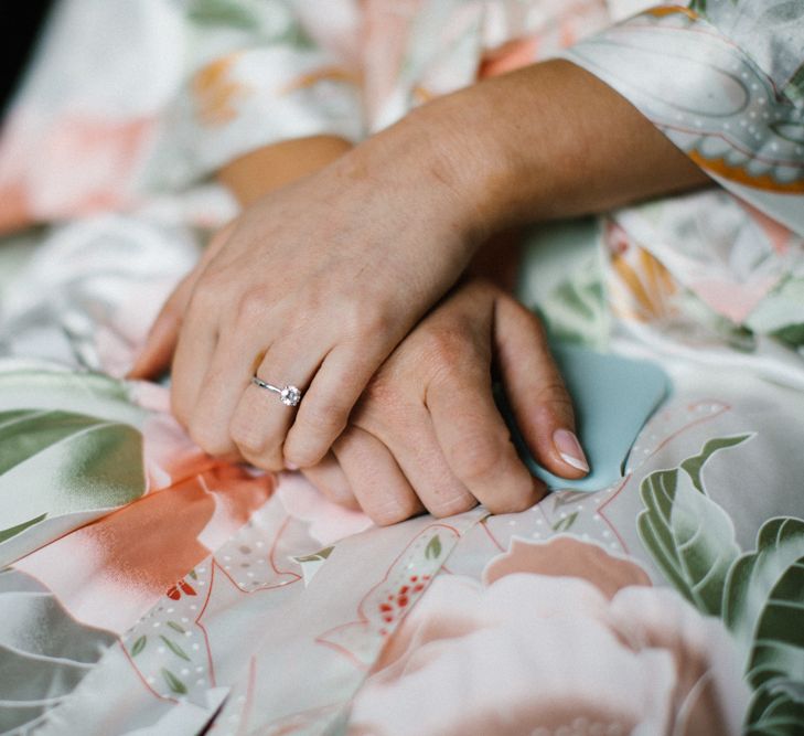 Bride in floral getting ready robe wearing her diamond engagement ring