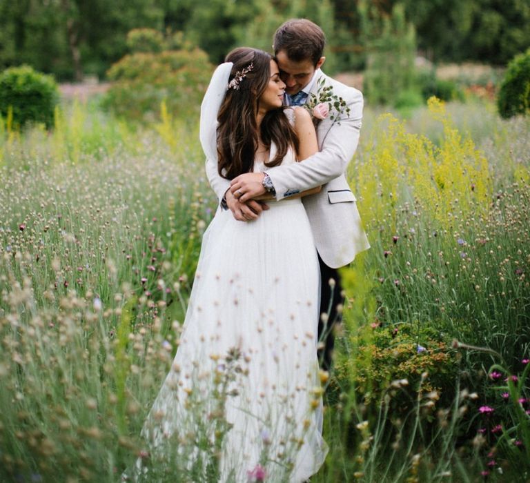 Groom in Beige Jacket Embracing His Bride in a Catherine Deane Wedding Dress