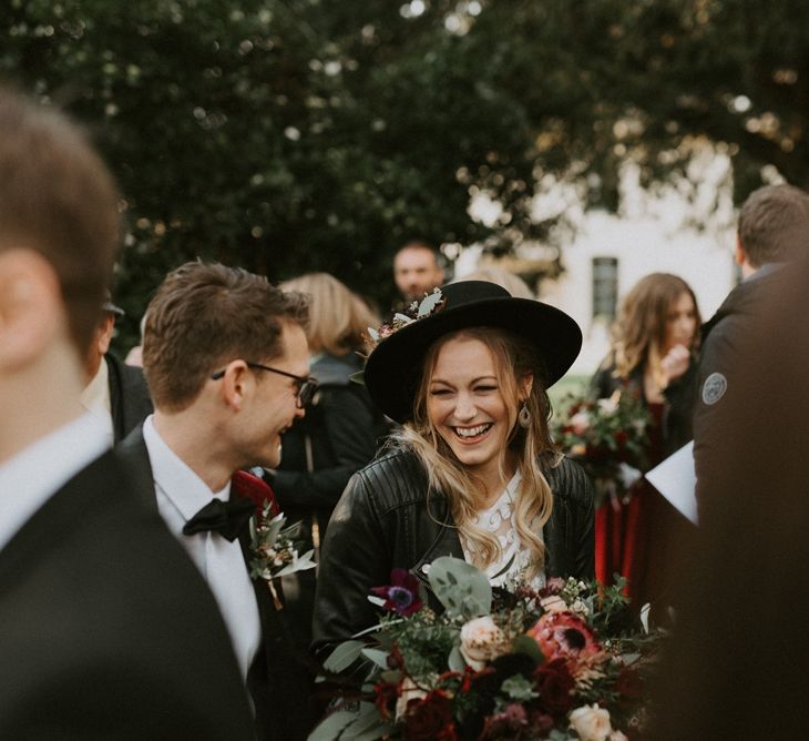 Bride in Fedora Hat and Leather Jacket Laughing Outside the Church