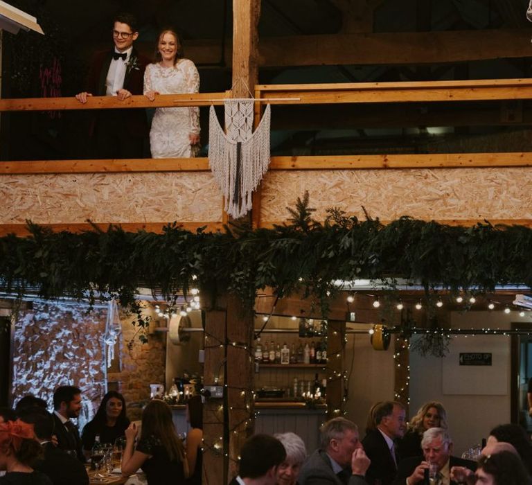 Bride and Groom Standing on the Mezzanine Looking at their Wedding Reception