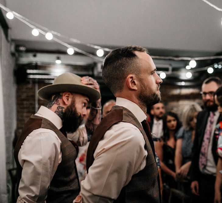 Groom standing at the altar in brown check waistcoat