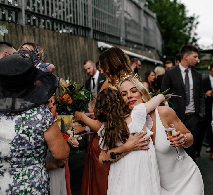 Stylish bride in gold crown hugging the flower girl