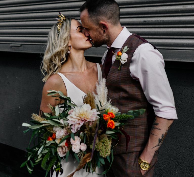 Stylish bride and groom kissing with bride in gold bridal crown