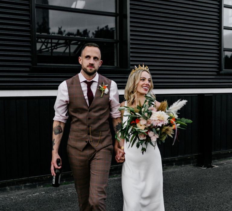 Stylish bride in minimalist wedding dress and groom in check trousers and waistcoat