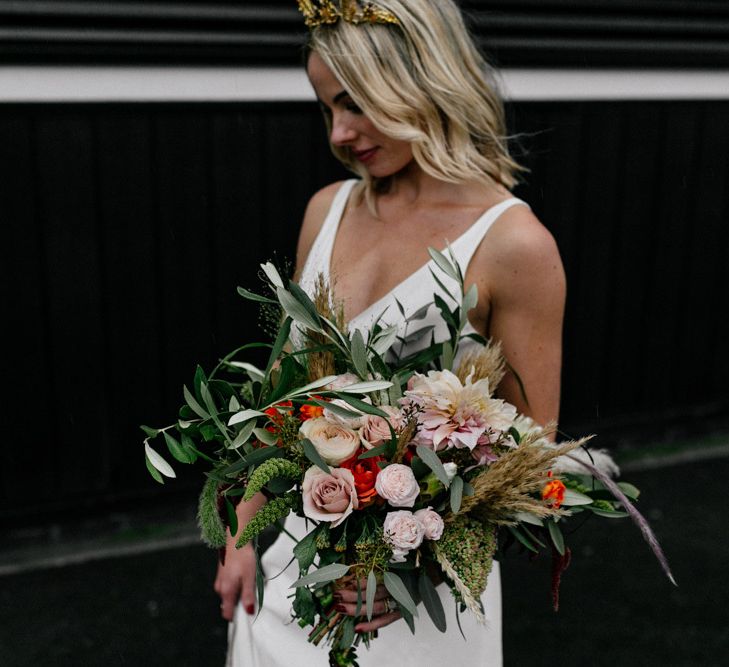 Stylish bride holding an oversized bouquet with  blush pink flowers and foliage