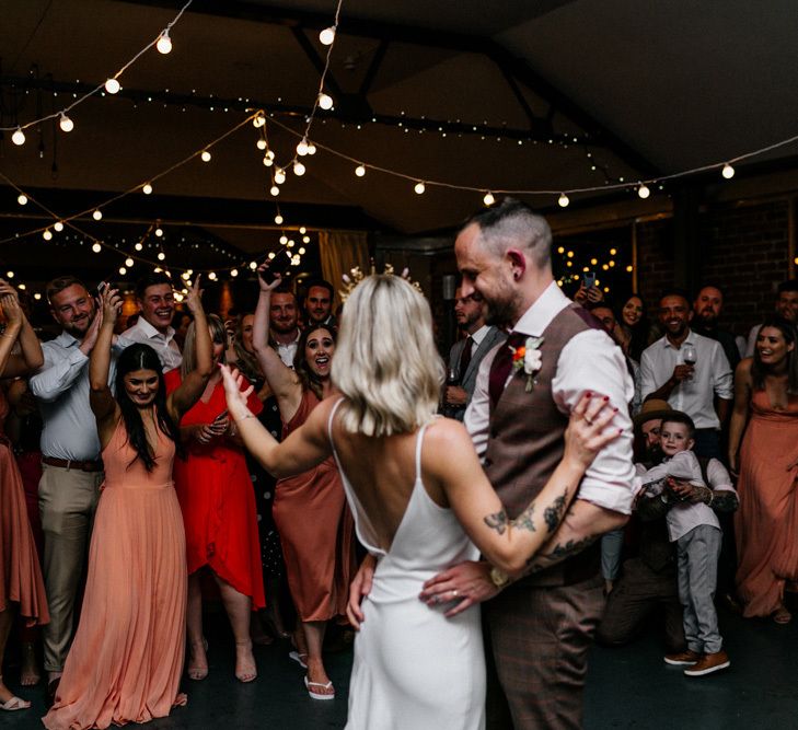 Bride and groom waving at wedding guests on the dance floor