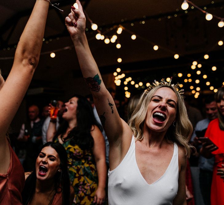 Bride in gold bridal crown and bridesmaids on the dance floor at evening reception