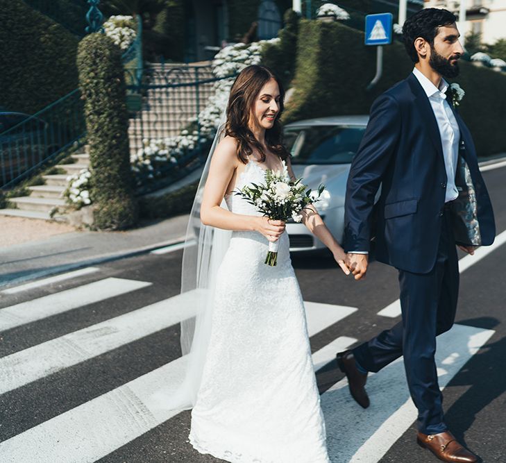 Bride in Grace Loves Lace Mia Wedding Dress and Groom in Taliare Navy Suit Walking Across a Zebra Crossing