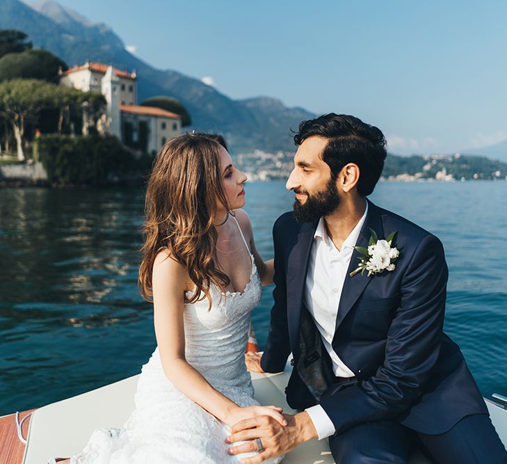 Bride in Grace Loves Lace Mia Wedding Dress and Groom in Taliare Navy Suit Enjoying a Boat Ride Over Lake Como