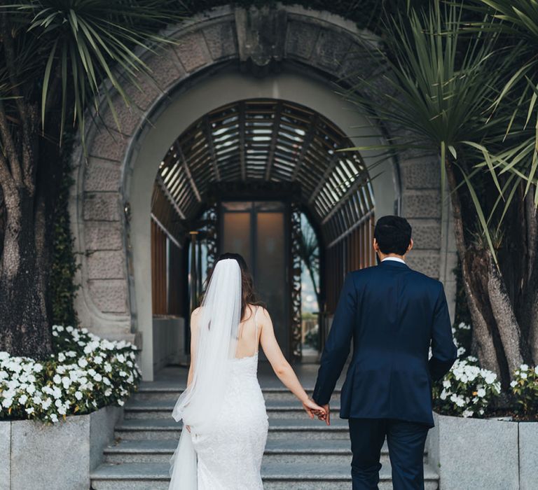 Bride in Grace Loves Lace Mia Wedding Dress and Groom in Taliare Navy Suit Going to Intimate Wedding Reception