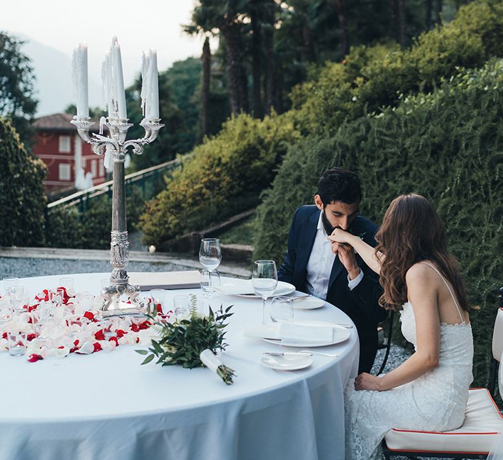 Groom in Taliare Navy Suit Kissing His Brides Hand at Their intimate Wedding Reception