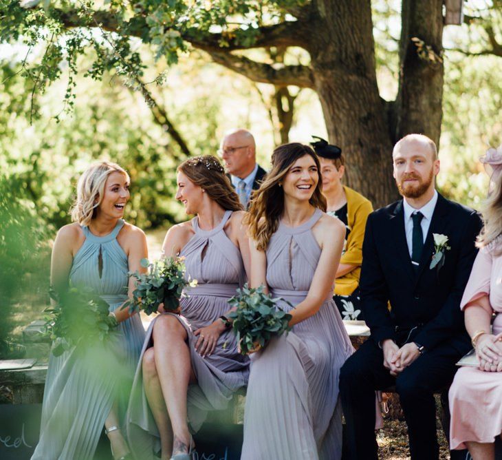 Bridesmaids in pastel halter neck dresses at outdoor woodland wedding in autumn