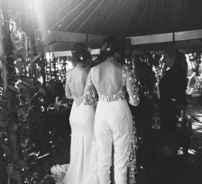 Back of brides appliqué wedding jumpsuit and elegant embellished dress at secluded woodland wedding