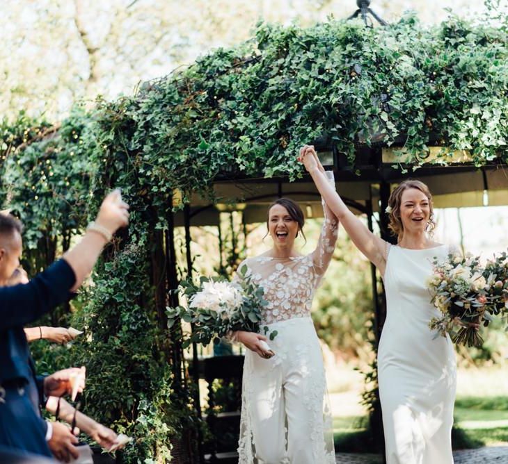 Two brides at same sex wedding at outdoor ceremony with gypsophila  decor