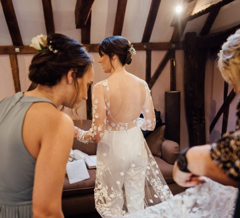 Back of brides appliqué wedding jumpsuit with low back detailing at woodland wedding celebration