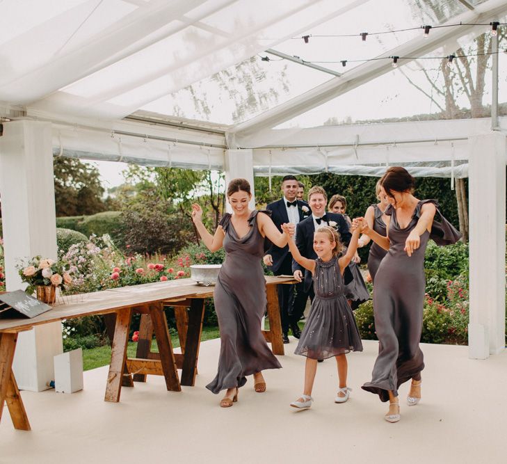 Bridal Party Entrance | Flowers from Topiary Tree | Bride in Karen Willis Holmes | Groom in Custom Made Suit by Suit Supply | Summer Wedding at Family Home in Kent | Glass Marquee from Academy Marquees | Frances Sales Photography