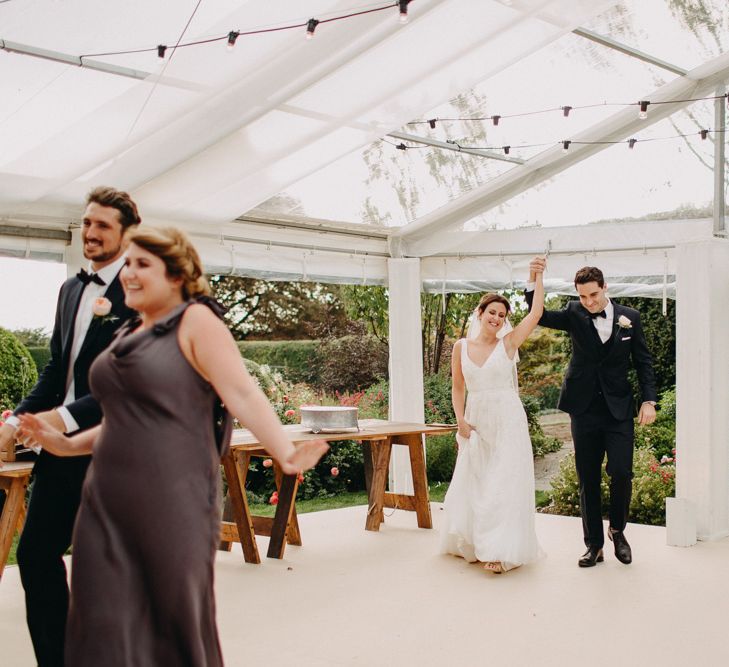 Bridal Party Entrance | Flowers from Topiary Tree | Bride in Karen Willis Holmes | Groom in Custom Made Suit by Suit Supply | Summer Wedding at Family Home in Kent | Glass Marquee from Academy Marquees | Frances Sales Photography