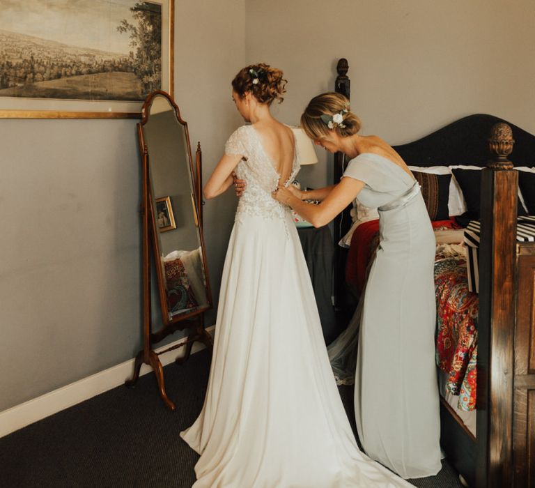 Bride with undo gets into wedding dress for Askham Hall wedding