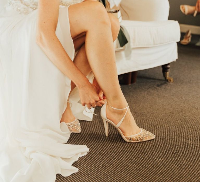 Bride  with undo puts on ivory wedding shoes for Askham Hall wedding