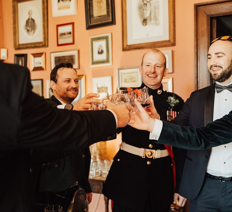 Groom and groomsmen in tuxedos toast the big day at Askham Hall wedding