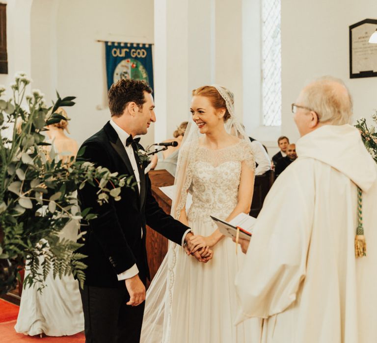 Bride in cap sleeve dress with veil at church ceremony