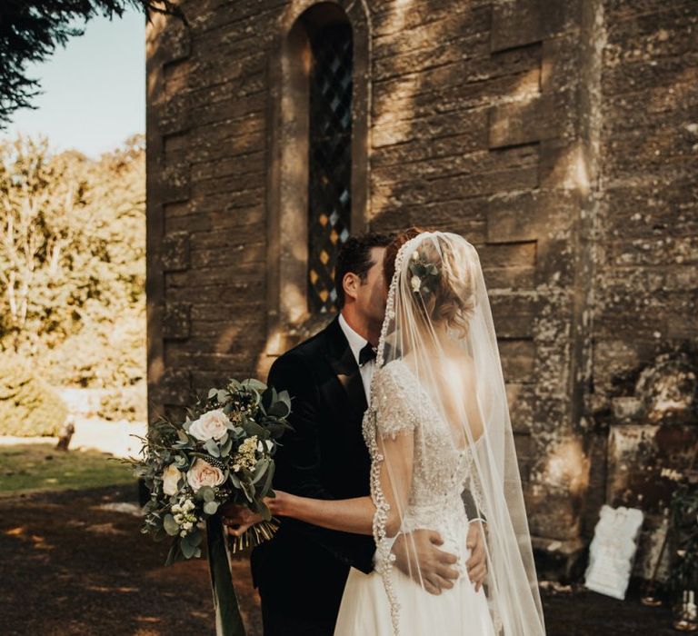 Bride in cathedral veil  with blush rose and foliage bouquet