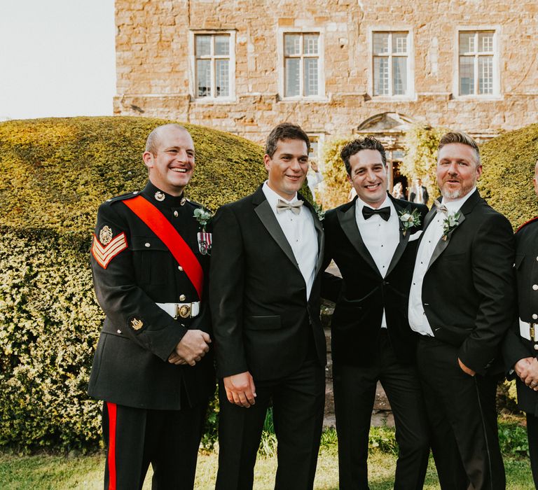 Groom with groomsmen in tuxedo and uniforms