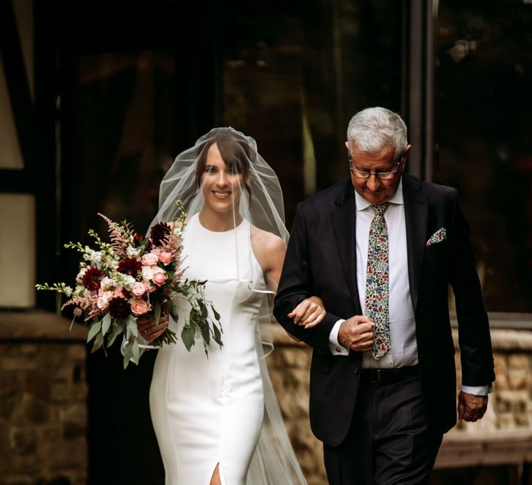 Bride walking down the aisle in fitted halter neck wedding dress