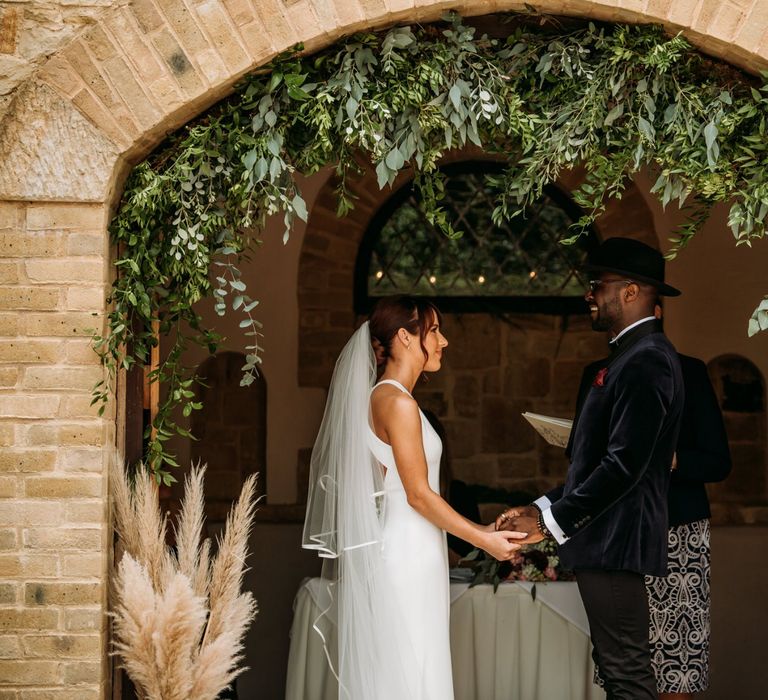 Outdoor wedding ceremony at The Ravenswood with bride and groom holding hands