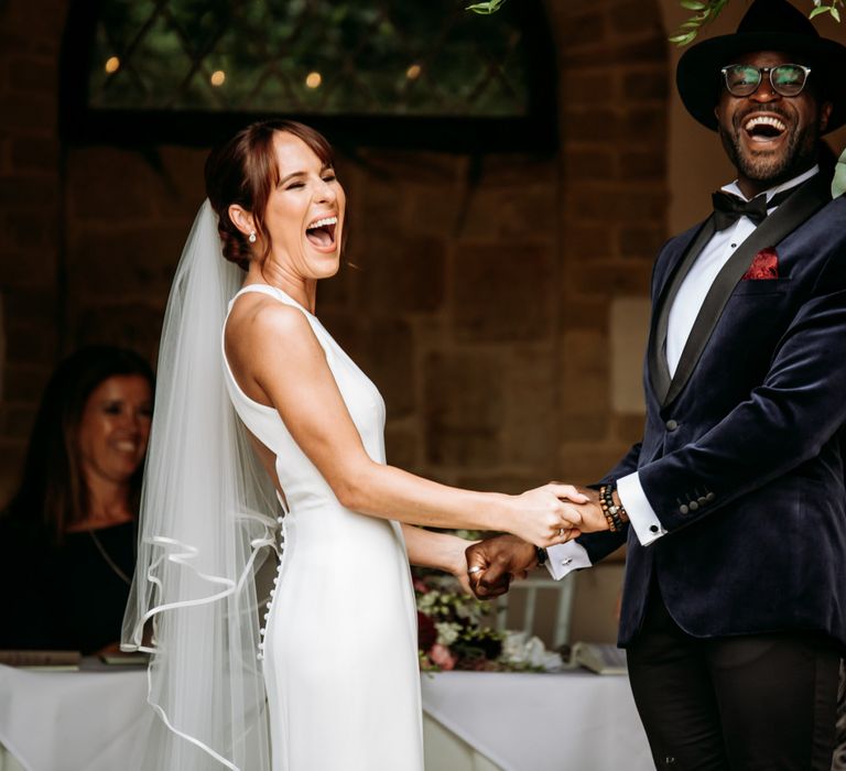 Bride and groom holding hands laughing at The Ravenswood wedding ceremony