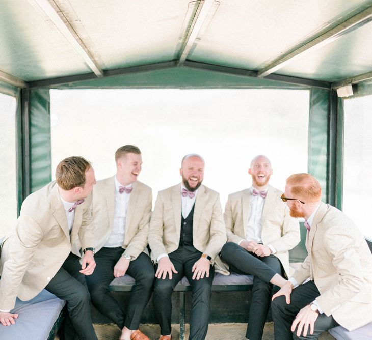 Groomsmen in Beige Jackets and Bow Ties on the Back of a Tractor