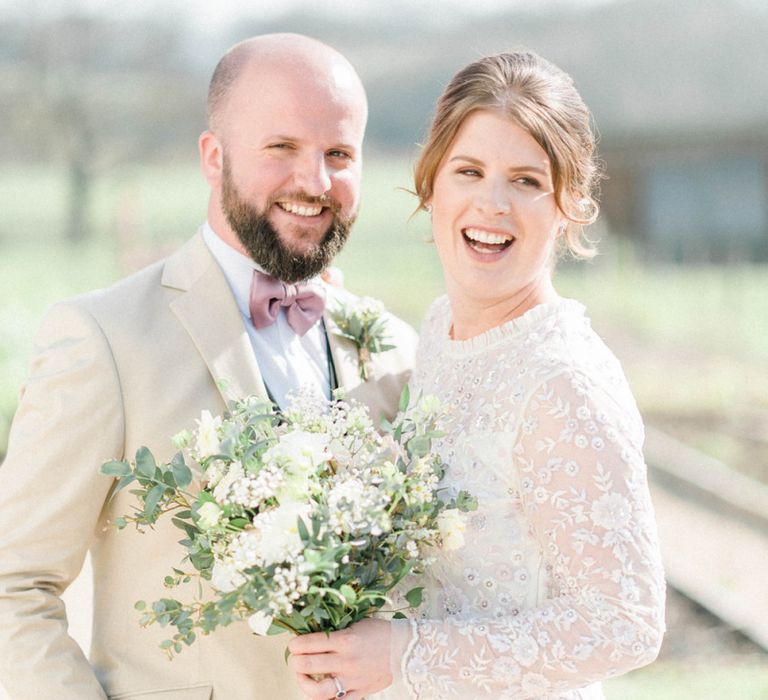 Bride in High Neck Needle &amp; Thread Wedding Dress and Bearded Groom in Bow Tie Laughing