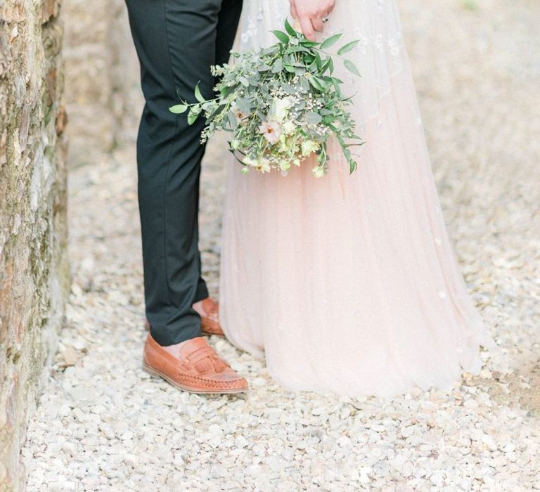 Groom in Black Chino's and Beige Blazer with Tan loafers and Bride in an Ombre Wedding Dress Holding a Bouquet by Her Side