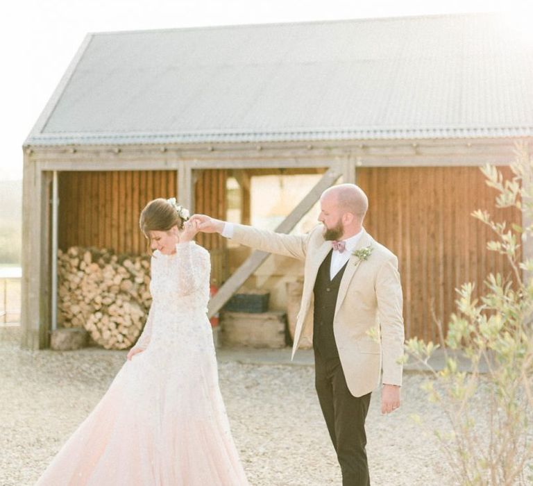 Groom in Beige Blazer and Pink Bow Tie Twirling His Bride in a Needle &amp; Thread Pink Ombre Wedding Dress