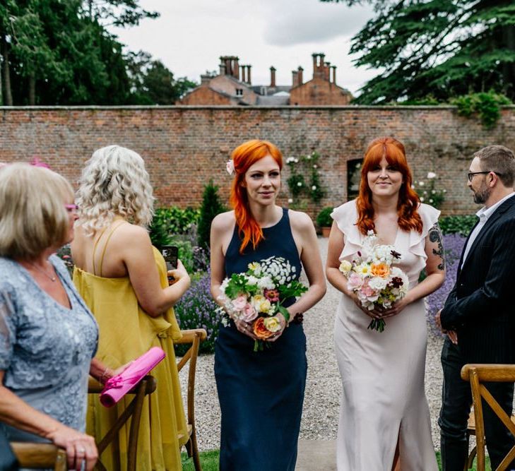 Two Bridesmaids In Navy And Pink Walk Down The Aisle