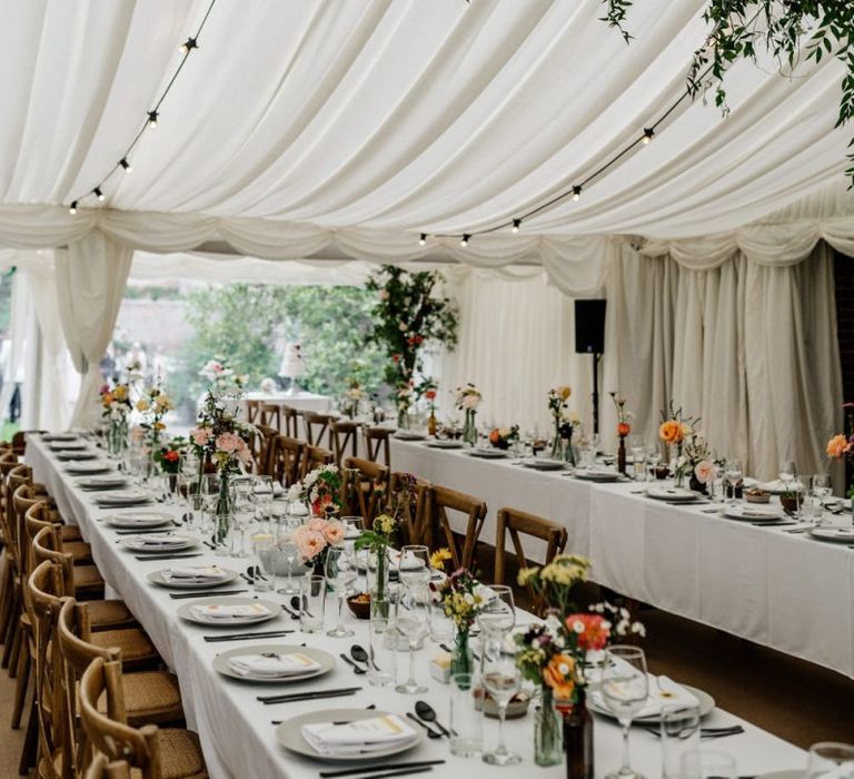 Marquee Reception with Floral Beam Hanging and Bright Flowers in Vintage Jars on Table