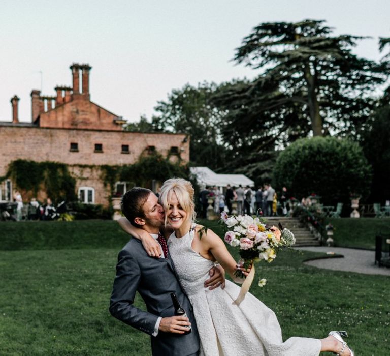 Groom Sweeps Bride of Feet While She Holds Bouquet