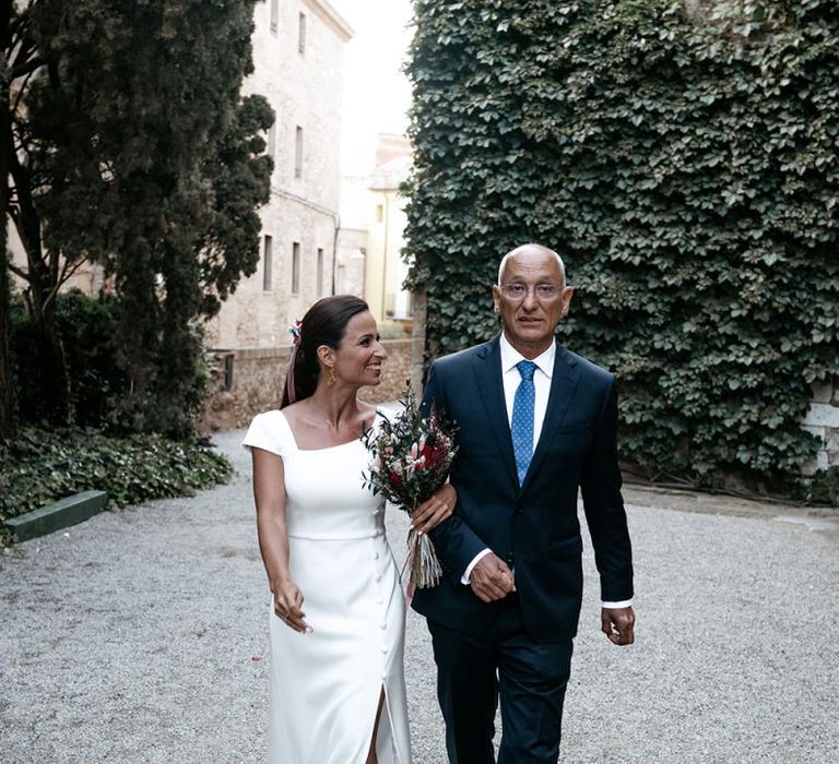 Brides in fitted wedding dresses with Father before outdoor  ceremony