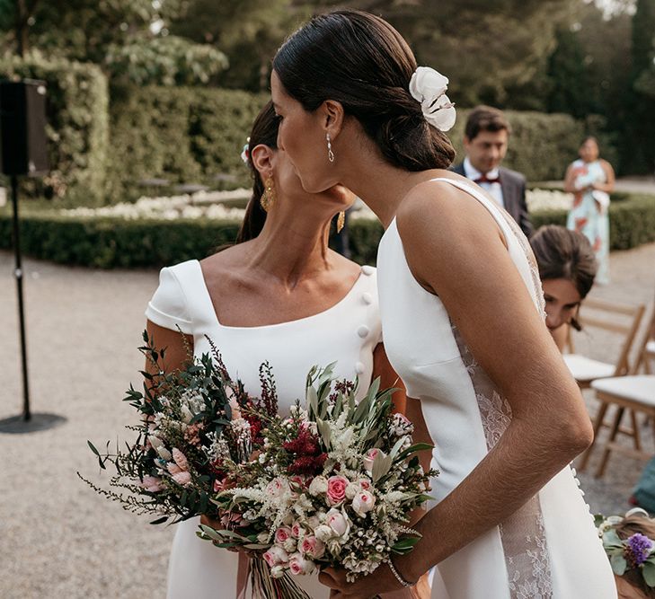 Bride greets wife to be at altar in fitted wedding dresses