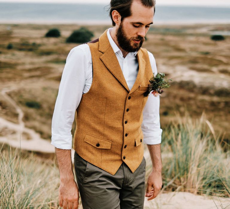 Groom in waistcoat at rustic wedding with globe guest book