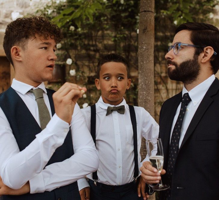 Page Boy in Braces and Bow Tie Making Face Whilst Wedding Guests are Talking