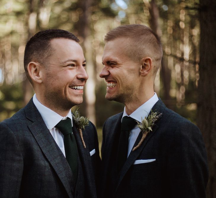 Two Grooms Smiling at Each Other in the Woods