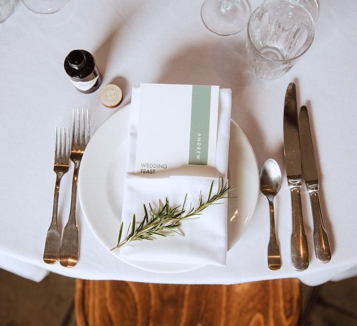 Place Setting with Menu Card Tucked into a Napkin and Decorated with a Rosemary Sprig