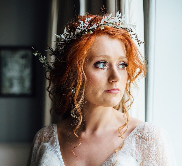 Bride in Lace Batwing Wedding Dress and Foliage Flower Crown Looking Out of a Window