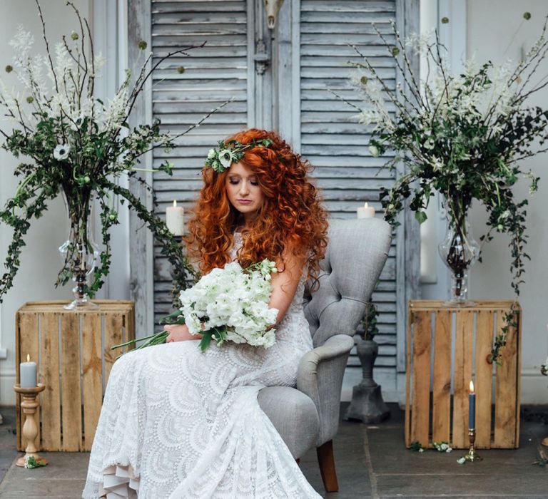 Bride in Lace Wedding Dress with Curly Hair Sitting on Grey Chair