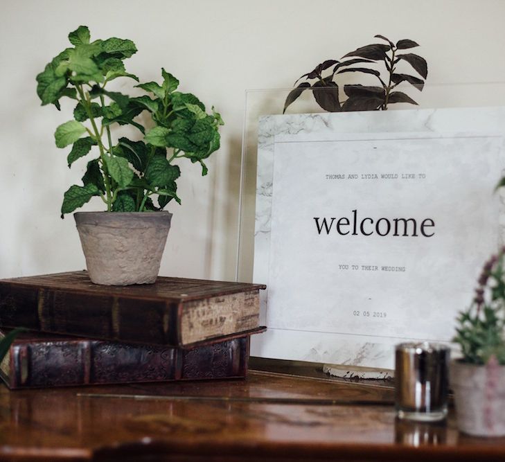 Marble and Acrylic Wedding Welcome Sign with Vintage Books and Potted Plant Decor