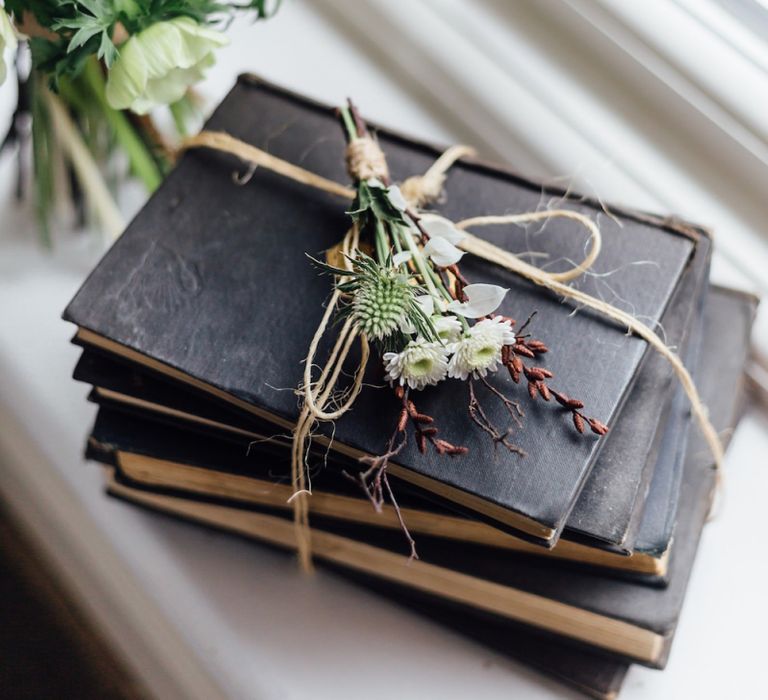 White and Green Buttonhole Resting on Pile of Antique Books