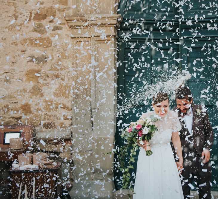 Confetti Exit | Bride in Sartoria Cucciaioni Wedding Dress | Groom in Brown Tweed Suit &amp; Bow Tie | Stylish Pink Wedding at Terzo di Danciano, Tuscany, Italy | Lucrezia Senserini Photography | Film by Righi Photography