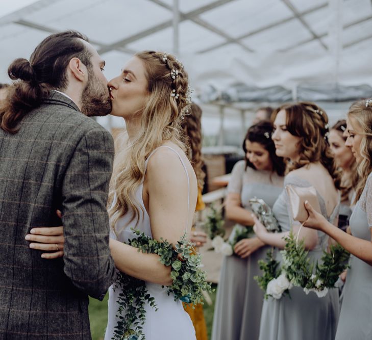 Boho Bride with Half Up Half Down Hair Kissing Groom with Top Knot