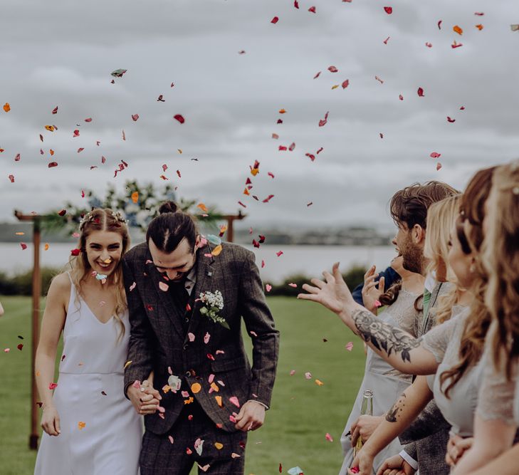 Colourful Confetti Moment with Bride in Slip Wedding Dress and Groom in Brown Check Suit